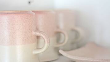 A close-up of ceramic mugs with a speckled design, a handle, and a logo with a flower and text.
