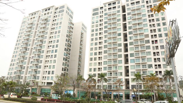 A high-rise residential building with multiple balconies and a ground-level commercial area.