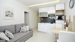 Une cuisine moderne avec des meubles blancs, un four encastré et un coin repas comprenant une table et des chaises.