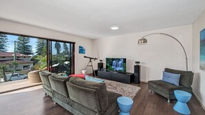 A modern living room with a large flat-screen TV, a telescope, and two sofas.