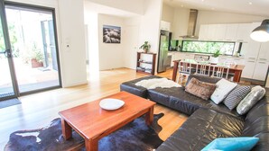 Una sala moderna con un sofá de cuero, una mesa de centro de madera y un comedor con una cocina al fondo.