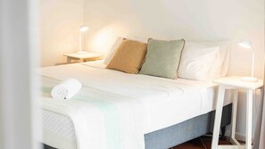 A neatly made bed with a white duvet, two pillows, and a rolled towel. There are two bedside tables with lamps, one on each side of the bed. - Beaches No 6 - Beachfront Views (Wongaling Beach)