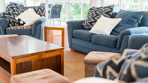 A living room with a blue sofa set, a wooden coffee table, and patterned throw pillows. - Beaches No 6 - Beachfront Views (Wongaling Beach)