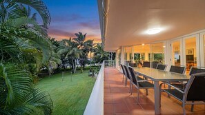 An outdoor dining area with a view of a garden and palm trees. - Beaches No 6 - Beachfront Views (Wongaling Beach)