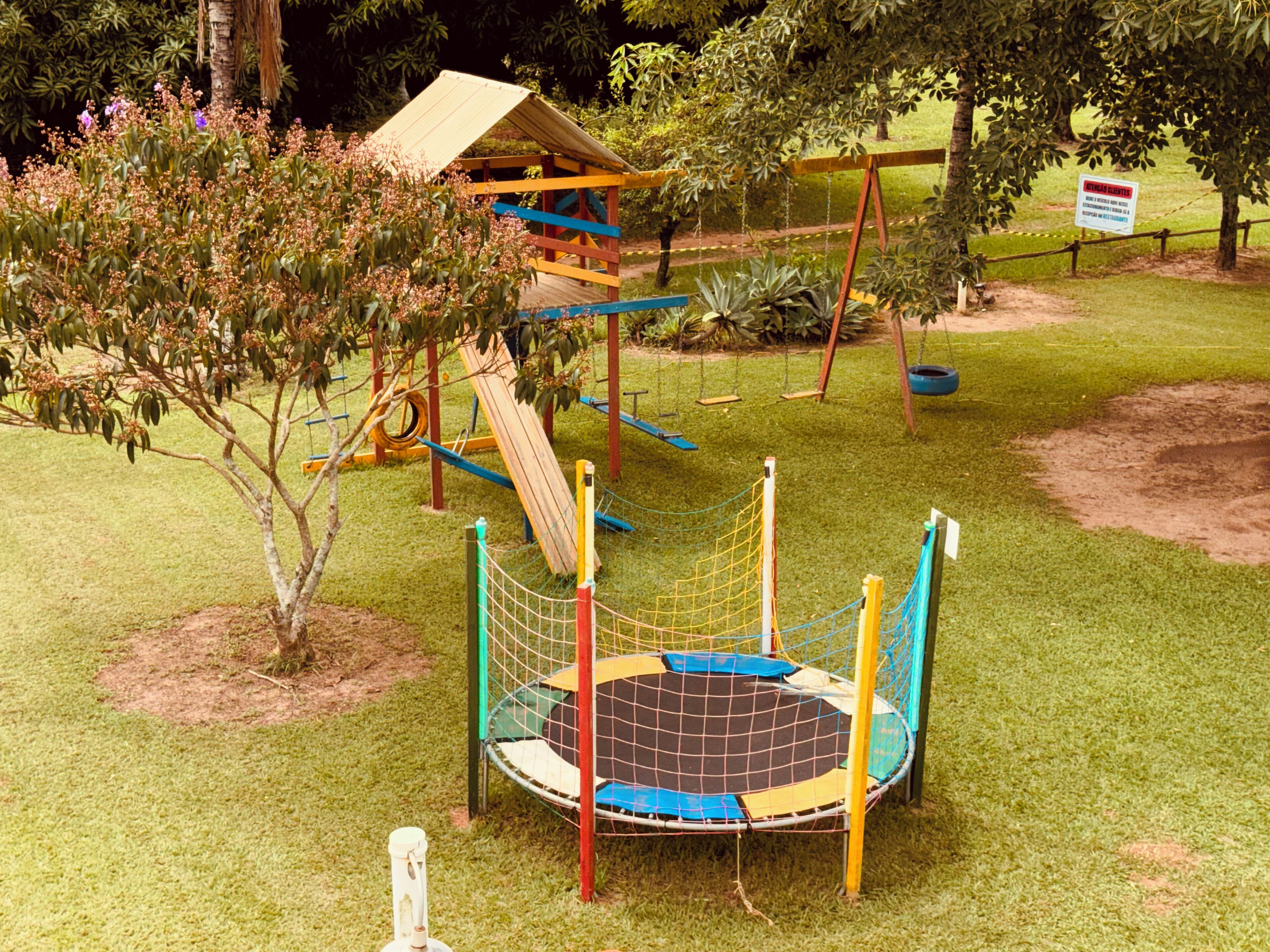 A playground with a swing set, slide, and climbing net.
