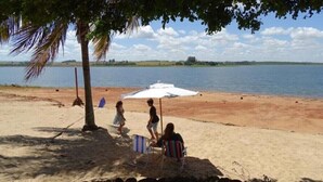 A beach with a sandy area, a few people, and a large body of water in the background. - Country house, heated pool, beach, tennis court, barbecue, playground, fishing, pets allowed. (Barão de Antonina)