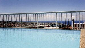 Une piscine offrant une vue sur une ville côtière et un ciel dégagé.