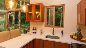 Een moderne keuken met houten kastjes, een wit aanrecht en een groot raam.