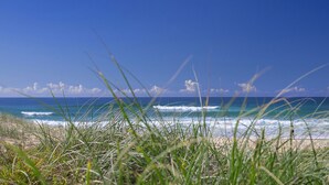 A beach with waves and grass in the foreground.