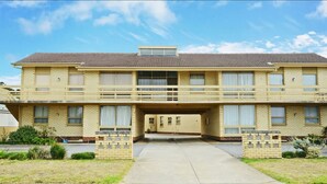 A two-story building with a flat roof, a central entrance, and a small balcony on the upper floor.