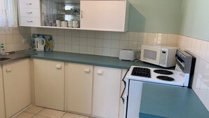 A kitchen with white cabinets, a microwave, a toaster, and a kettle on the counter.