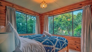 Un dormitorio de cabaña de madera con cama, cortinas y una araña.