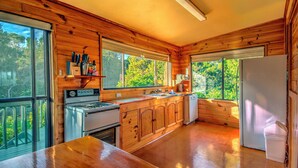 Cocina rústica de cabaña con una ventana grande, una estufa y un refrigerador.