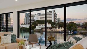 A modern living room with a large window overlooking a river and cityscape.