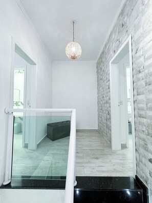 A modern interior with a staircase, a hanging light fixture, and a view into another room. - House for vacation in Maranduba/Ubatuba (Maranduba)