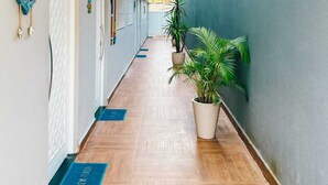 Un largo pasillo con puertas, plantas en macetas y un felpudo azul en el suelo.