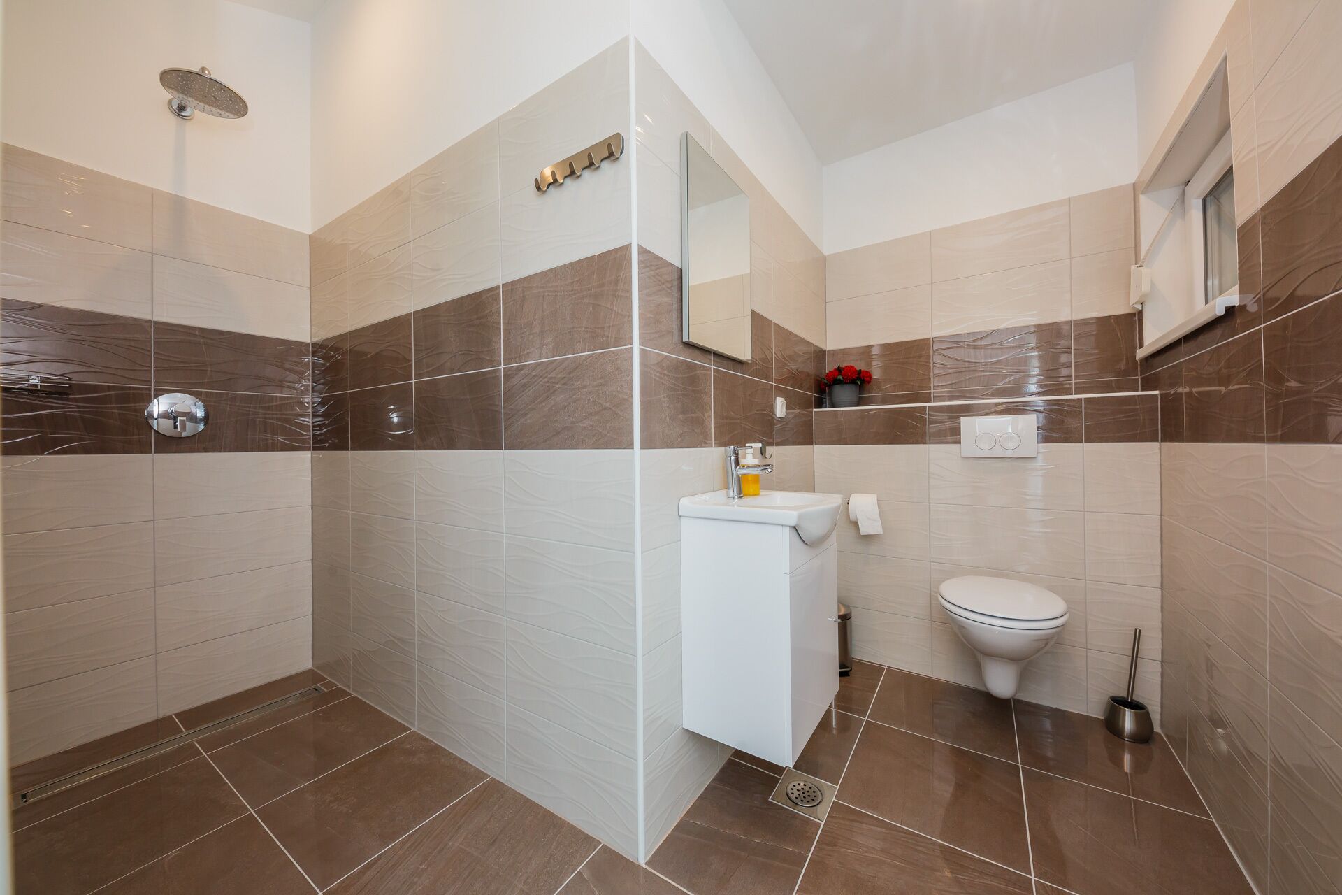 A modern bathroom with a shower, toilet, and sink.