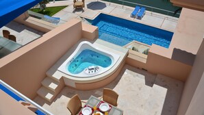 Un espace piscine aménagé sur le toit, comprenant un jacuzzi, des chaises longues et une table à manger avec des produits pour le petit-déjeuner.