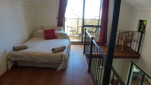 Un dormitorio con cama, ventana y balcón.