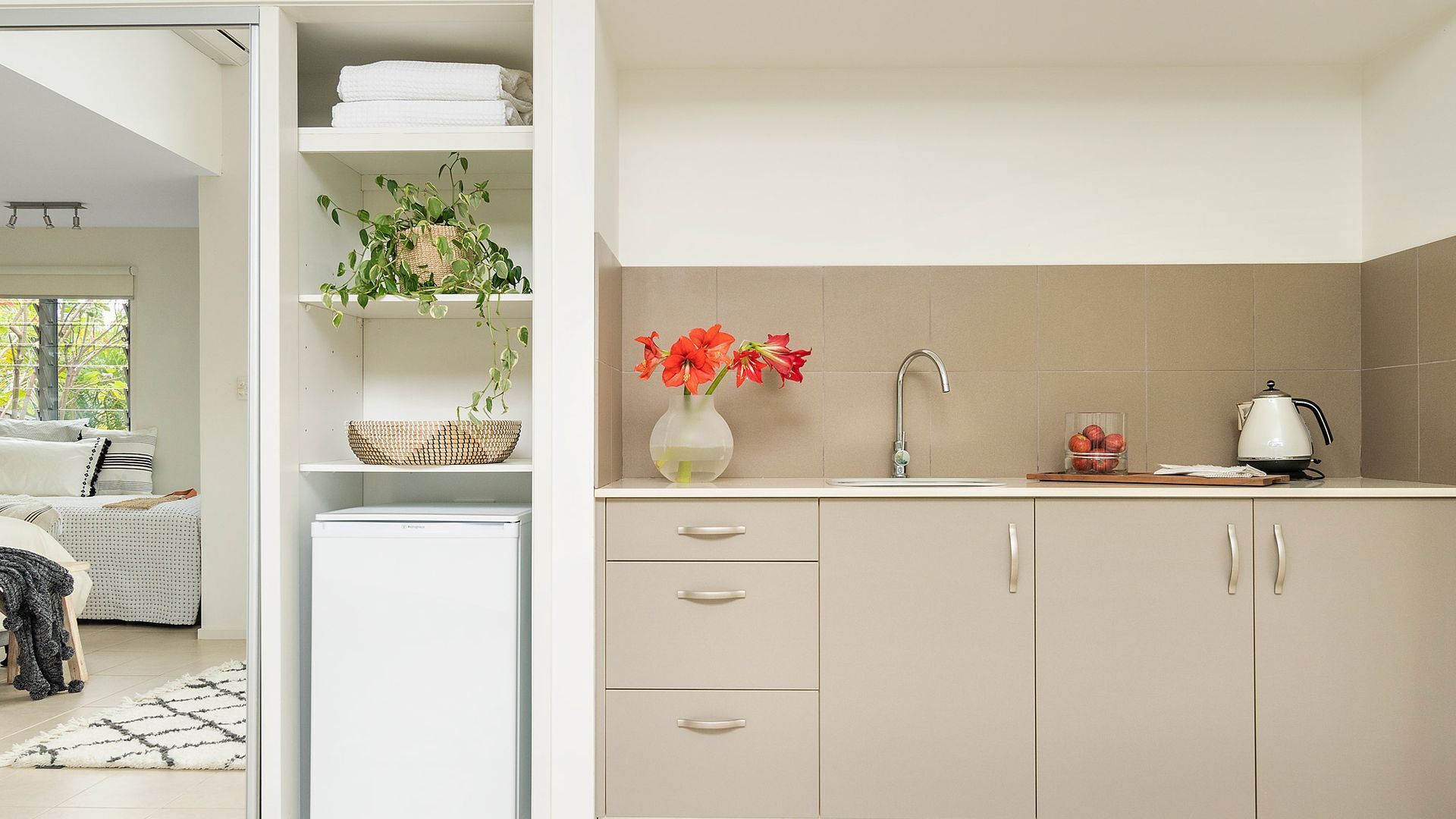 A modern kitchen with a built-in dishwasher, a sink with a faucet, and a stove. There is a vase with flowers on the countertop.