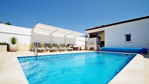 A swimming pool with lounge chairs and a covered seating area.