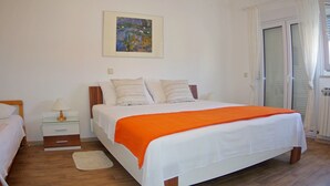 A bedroom with a bed, nightstands, a lamp, a painting, and a window with curtains.