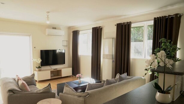A modern living room with a sofa set, a coffee table, a TV, and a plant.