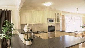 A modern kitchen with white cabinets, a central island, a microwave, an oven, and a sink.