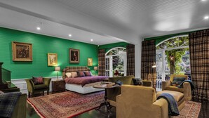 Une pièce avec un mur vert, un grand lit, un canapé et une table.