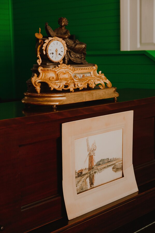 Un escritorio de madera con un reloj decorativo que muestra una figura sentada y un cuadro con una foto de un puente.