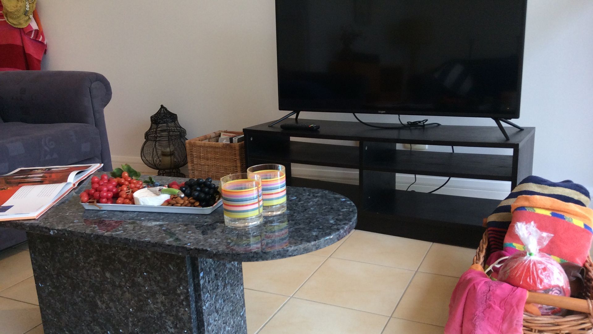 Un salon avec un téléviseur, une table basse avec des collations, un canapé et un panier.