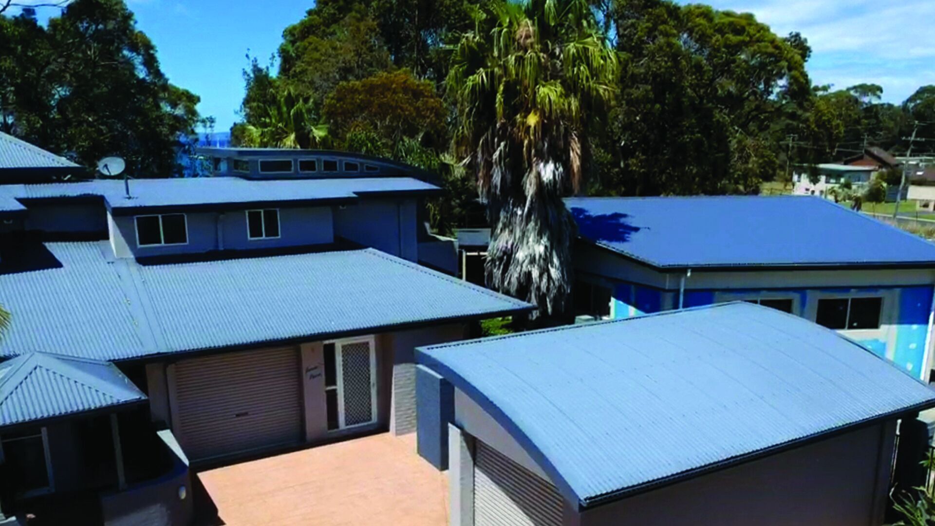 Zona residencial amb diverses cases que tenen teulades blaves i parets de metall ondulat.