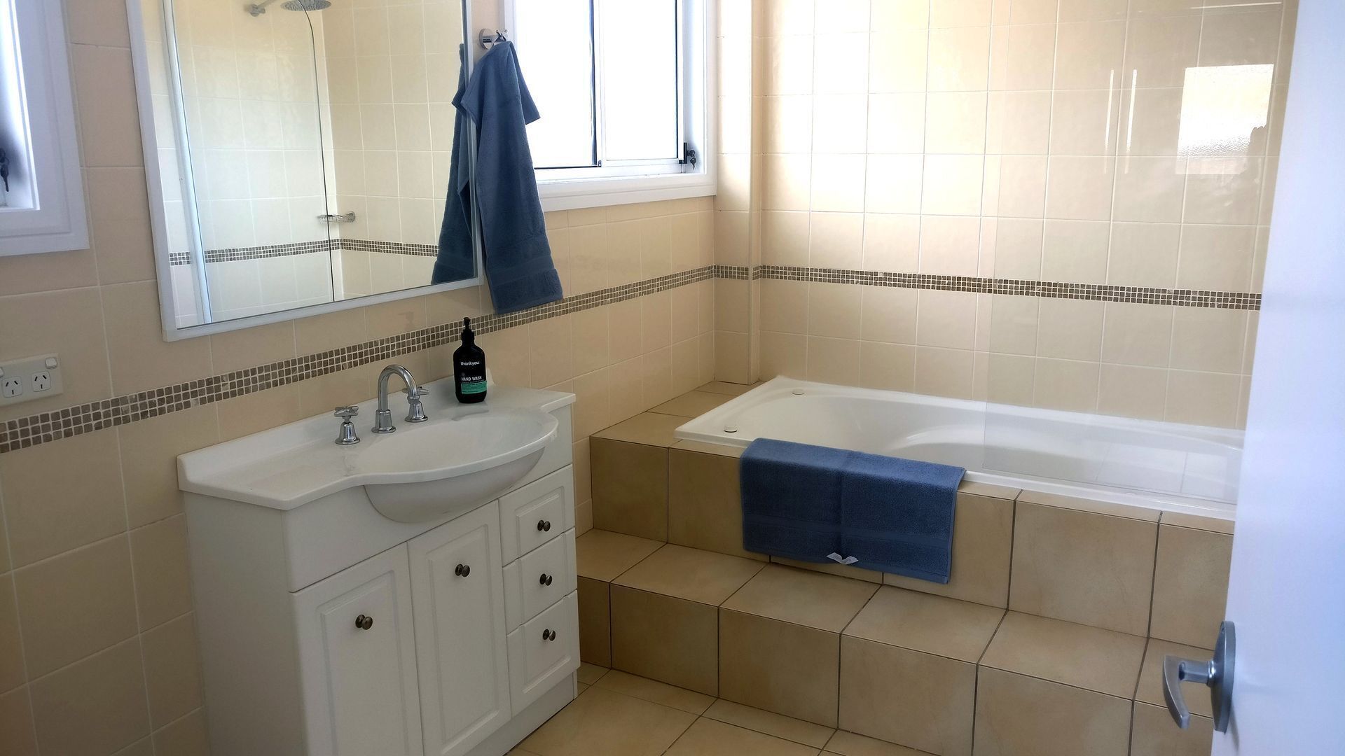 A bathroom with a sink, mirror, and bathtub.