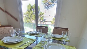 A dining area with a glass table set for four, surrounded by cushioned chairs. - Duplex apartment. One block from the Stone Cathedral. (Canela)
