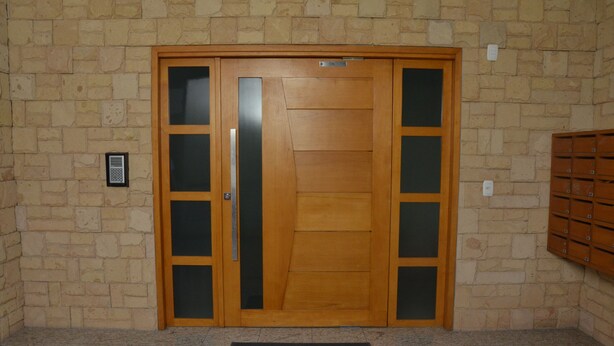 A wooden door with frosted glass panels, a mailbox, and a doormat with a name. - Duplex apartment. One block from the Stone Cathedral. (Canela)