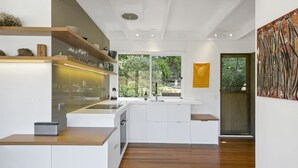 Een moderne keuken met witte kasten, een houten aanrecht en een groot raam met uitzicht op groen.