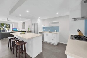 A modern kitchen with a central island, bar stools, a built-in oven, and a large window.