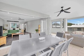 A modern living room with a glass dining table, white sofas, and a ceiling fan. - Turquesa at Island Views—Beachfront Resort Living (Palm Cove)