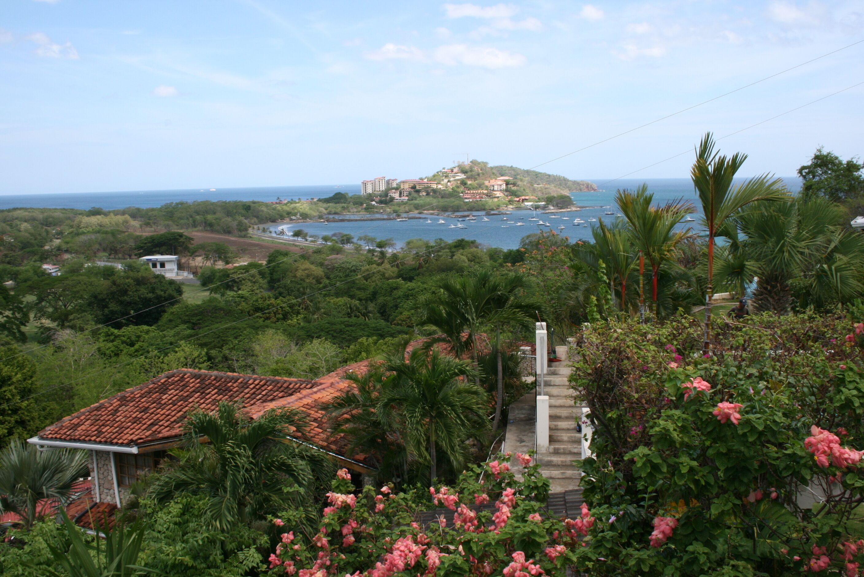 Une vue sur la côte, avec un bâtiment situé sur une colline, une végétation luxuriante et un ciel dégagé.