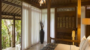 A spacious room with a large bed, a potted plant, and a view of greenery outside. - Citrus Tree Villas - Layla (Legian)
