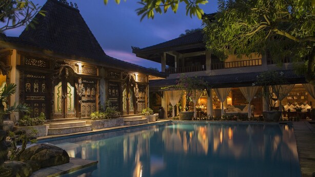 A pool area with a traditional building, a covered seating area, and a well-maintained garden. - Citrus Tree Villas - Layla (Legian)