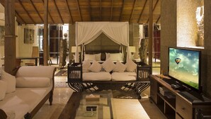 A spacious living area with a large bed, a sofa, and a television. - Citrus Tree Villas - Layla (Legian)