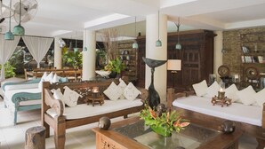 A spacious living room with a sofa set, a coffee table, and a bookshelf. - Citrus Tree Villas - Layla (Legian)