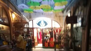 A spacious indoor area with tiled flooring, a central seating area with chairs, and a storefront with colorful umbrellas. - Inchy Accommodation (Split)