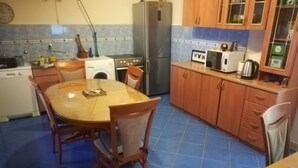 A compact kitchen with a round wooden table and chairs, a washing machine, a refrigerator, and a microwave. - Inchy Accommodation (Split)