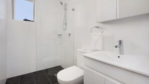 Une salle de bain moderne équipée d’une douche, de toilettes et d’un lavabo.