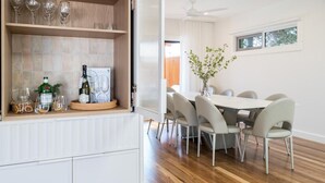 Un'area pranzo con tavolo e sedie, una dispensa per vini con bicchieri e una bottiglia sul bancone.