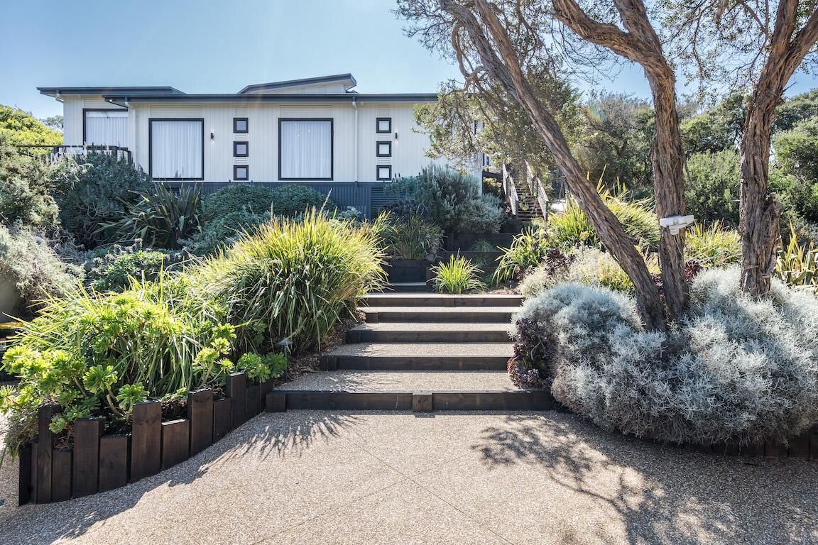 A modern house with a paved driveway leading to a set of stairs.