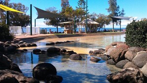 A clear pool with rocks, a gazebo, and a view of the ocean. - "Redcliffe Villa" - Redcliffe Q 4020 (Redcliffe)