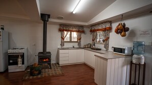 A kitchen with a wood-burning stove, a microwave, and a water dispenser. - Charming Rural Escape in Mumballup - Views, Fire Pit, Walks & Pet-Friendly Stay (Mumballup)